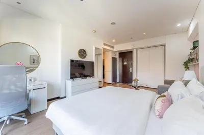 a white bedroom with a white bed and a couch at HAVN - Studio Dubai Marina View in Dubai