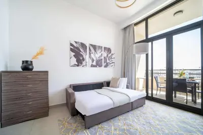 a bedroom with a bed and a balcony with a table at Frank Porter - Parkside Rawda 4 in Dubai