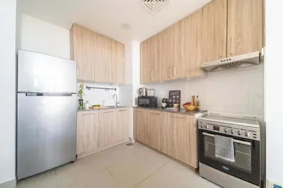 a kitchen with wooden cabinets and a stainless steel refrigerator at Frank Porter - Parkside Rawda 4 in Dubai