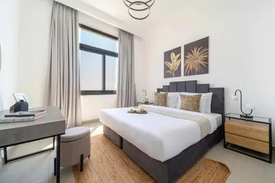 a bedroom with a king sized bed and a desk at Frank Porter - Parkside Rawda 4 in Dubai