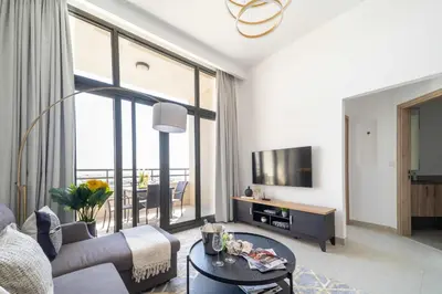 a living room with a couch and a tv at Frank Porter - Parkside Rawda 4 in Dubai