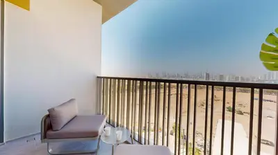 a room with a chair and a balcony with a view at Mag Eye 910 - Tranquil Studio Apartment in Meydan in Dubai