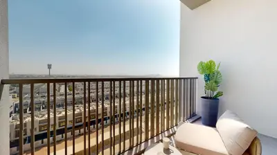 a balcony with a white chair and a plant at Mag Eye 920 - Classy Studio Apartment in Meydan in Dubai