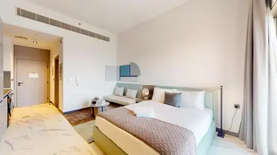 a white bedroom with a bed and a couch at Vacationer I Stylish Studio I Skyline & Community Views I 12 Mins to Downtown I MAG Eye 910 in Dubai
