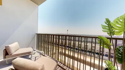a room with a chair and a balcony with a view at Mag Eye 910 - Peaceful Studio Apartment in Meydan in Dubai