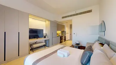 a bedroom with a white bed and a television at Mag Eye 930 - Calm Studio Apartment in Meydan in Dubai