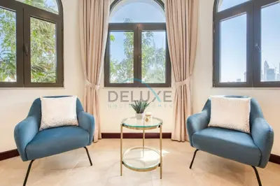 two blue chairs and a table in a room with windows at Prestigious 5BR Villa with Assistant Room and Private Pool in Frond O Palm Jumeirah by Deluxe Holiday Homes in Dubai