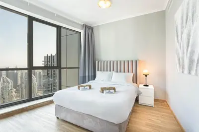 a bedroom with a large white bed and large windows at Cozy Home at the Heart of Marina on 52nd Floor in Dubai