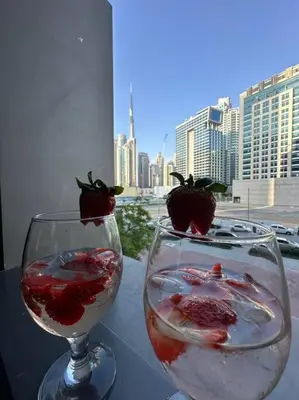 two wine glasses with strawberries in them on a table at Studio with Terrace Damac Maison Cour Jardin Business Bay in Dubai