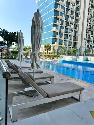 a group of lounge chairs and umbrellas next to a pool at Burj Khalifa view modern 1BHK with balcony in Dubai