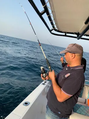 a man fishing on a boat in the water at Burj Khalifa view modern 1BHK with balcony in Dubai