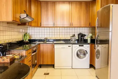 a kitchen with wooden cabinets and a washer and dryer at Lux two br w Sea Views from rooms in Dubai Marina in Dubai