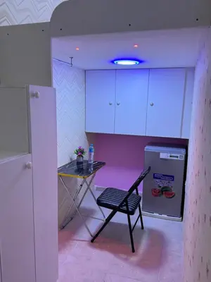 a kitchen with a table and a chair and a refrigerator at Loft bed short and long stay in Dubai