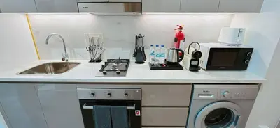 a kitchen with a sink and a stove and a microwave at Elegant Studio Apartment In Meydan One in Dubai