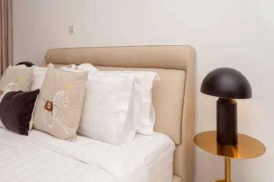 a bed with white pillows and a black lamp at Prime retreats - steps to Grosvenor Hotel in Dubai