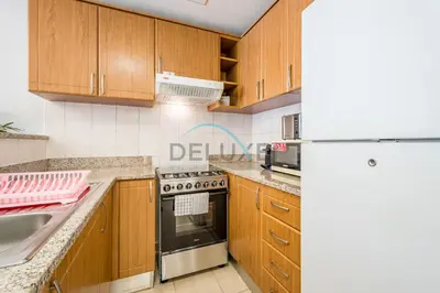 a kitchen with wooden cabinets and a stove top oven at Contemporary Studio in Manara 6, Jebel Ali by Deluxe Holiday Homes in Dubai