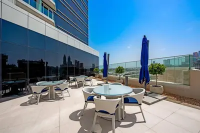 a patio with tables and chairs and blue umbrellas at GLOBALSTAY Palm View in Dubai