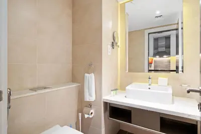 a bathroom with a sink and a toilet and a mirror at DAMAC MAISON PRIVE - Lake View in Dubai