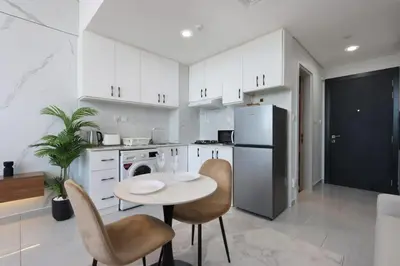 a kitchen with white cabinets and a table and chairs at Modern Studio in JVC, Near Parks and Highways in Dubai