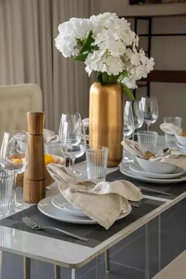 a table with plates and glasses and a vase with flowers at Frank Porter - Creek Edge Tower 1 in Dubai