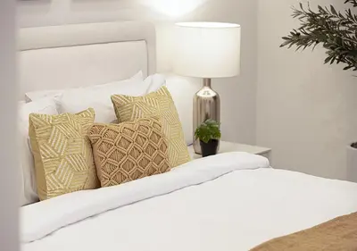 a white bed with pillows and a lamp on a table at Princess Tower - Spectacular Sky Views, Palm Jumeirah & JBR Beach in Dubai