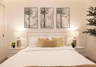 a bedroom with a white bed with three paintings on the wall at Princess Tower - Spectacular Sky Views, Palm Jumeirah & JBR Beach in Dubai