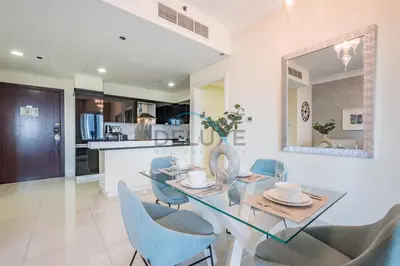 a dining room with a glass table and blue chairs at Whimsical 3BR at The Signature, Downtown Dubai by Deluxe Holiday Homes in Dubai