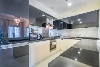 a large kitchen with white cabinets and black appliances at Whimsical 3BR at The Signature, Downtown Dubai by Deluxe Holiday Homes in Dubai