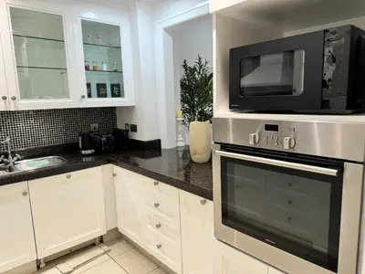 a kitchen with white cabinets and a microwave at Luxurious 1BR Aprt Burj Khalifa Area in Dubai