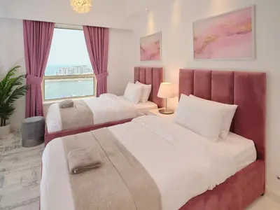 two beds in a hotel room with a window at JBR Beachfront Luxe apartment all Rooms Sea Facing in Dubai