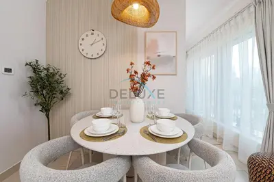 a dining room with a table and chairs and a clock at Chic Studio in Burj Views Podium, Downtown Dubai by Deluxe Holiday Homes in Dubai