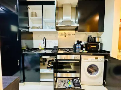 a kitchen with a stove and a washing machine at Lovely Studio in Damac Maison Cour Jardin Business Bay in Dubai