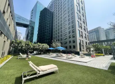 a park with lounge chairs on the grass in a city at Lovely Studio in Damac Maison Cour Jardin Business Bay in Dubai
