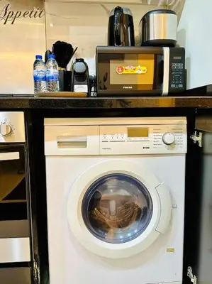a washing machine under a counter in a kitchen at Lovely Studio in Damac Maison Cour Jardin Business Bay in Dubai