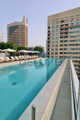 a large swimming pool with chairs and buildings at Modern 2BR in VIDA Residences Dubai Marina by Deluxe Holiday Homes in Dubai