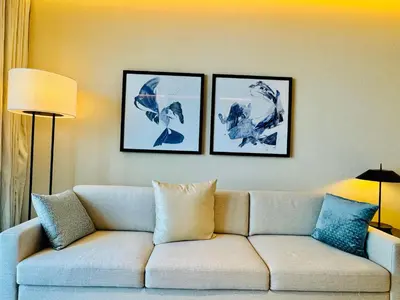 a living room with a couch and three pictures on the wall at Skyline Retreat 3 Bedroom at Address Opera I Burj Khalifa & Fountain Views in Dubai
