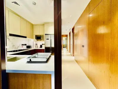 a kitchen with white counters and wooden cabinets at Skyline Retreat 3 Bedroom at Address Opera I Burj Khalifa & Fountain Views in Dubai
