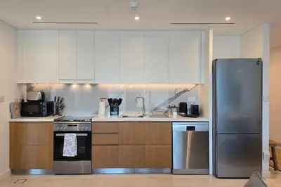 a kitchen with white cabinets and a stainless steel refrigerator at Private Spa 1BR Biophilic Retreat With Beach Access & Infinity Pool in Dubai