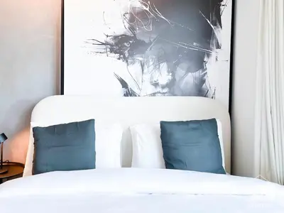 a white bed with two blue pillows in a bedroom at Breath taking Studio with Balcony & Stunning Views in Dubai