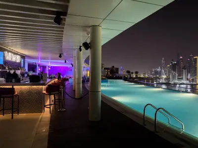 a rooftop bar with a view of the city at night at Beachfront 1 Bedroom Apartment on Palm Jumeirah with Stunning Sea Views and Rooftop Infinity Pool in Dubai