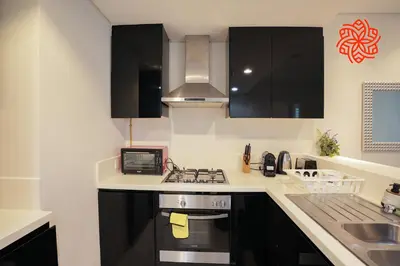 a kitchen with black cabinets and a stove top oven at Alashrafia Saray- Upscale 1bdr apartment in Canal Views in Dubai