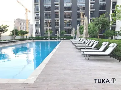 a row of lounge chairs and umbrellas next to a pool at Stunning 2-BHK Golfville at Dubai Hills Prime in Dubai