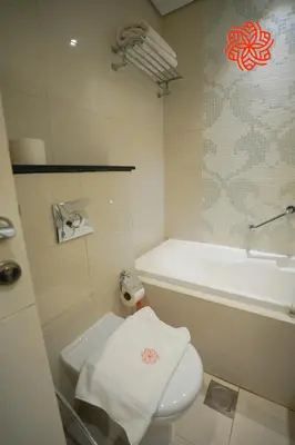 a bathroom with a white toilet and a tub and a towel at Alashrafia Saray- Peaceful studio in Canal Views in Dubai