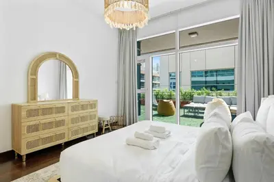 a bedroom with a white bed and a large window at DAYF-ALI City's Heart Chic 1 BR Huge Terrace and Great Access in Dubai