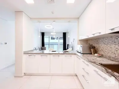 a kitchen with white cabinets and a counter top at Modern 1B with Balcony, Gym & Pool Access in Dubai