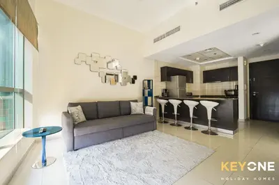 a living room with a couch and a kitchen at Contemporary One Bedroom with Full Marina View in Dubai