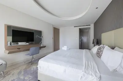 a white bedroom with a large bed and a tv at Cozy 1BR with balcony great view, Damac Towers in Dubai