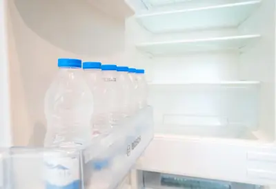 three bottles of water in an open refrigerator at Luxury 3BR Burj Khalifa View Infinity Pool Spa Gym in Dubai