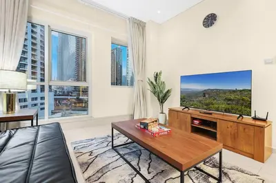 a living room with a couch and a table and a tv at FIRST CLASS 1BR Charming Marina Escape in Dubai