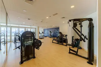 a gym with several tread machines in a room at Dejaview Stays Luxury Apartment with Private Terrace, Burj & Sea View in Dubai